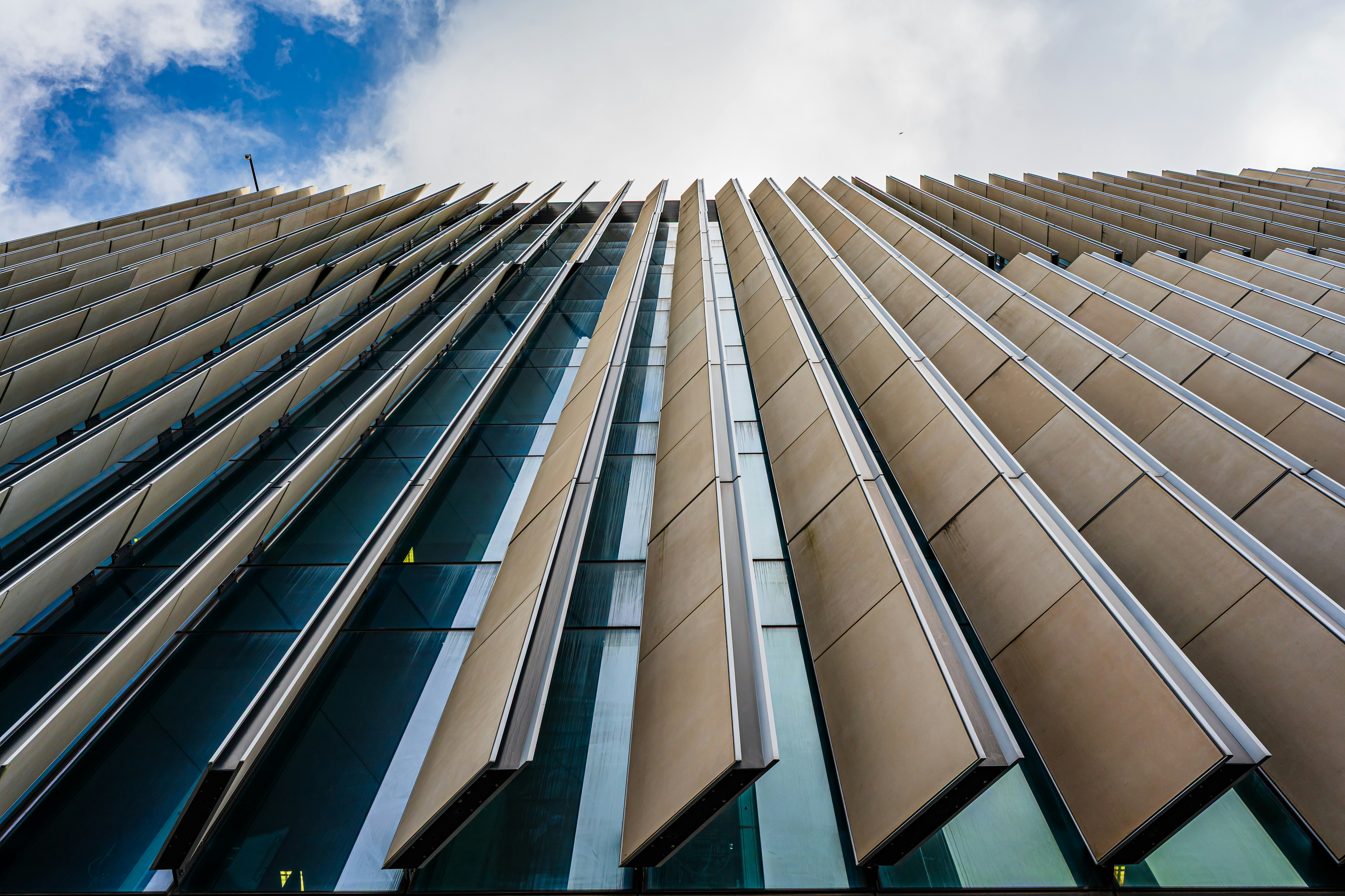 The image shows a tall glass building with wooden panels.