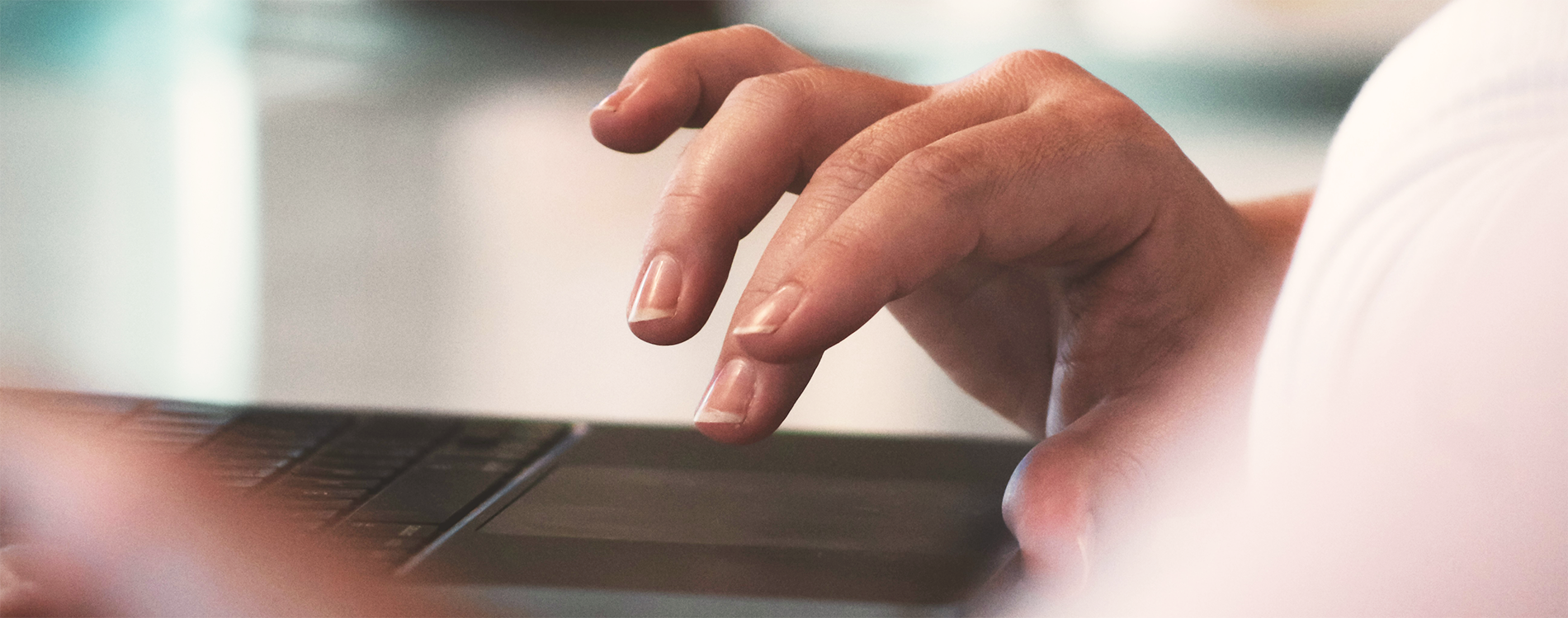 The image shows a hand moving towards a computer keyboard.